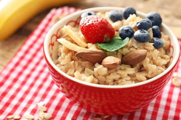 Leckere Haferflocken mit Beeren und Früchten in Schüssel auf dem Tisch — Stockfoto