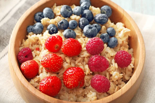 Leckere Haferflocken mit Beeren in Schüssel auf dem Tisch, Nahaufnahme — Stockfoto