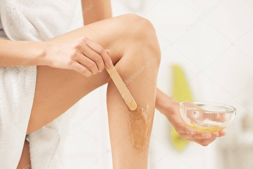 Young woman depilating leg