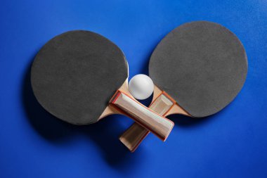 İki ping pong raketleri ve mavi arka plan üzerinde topu