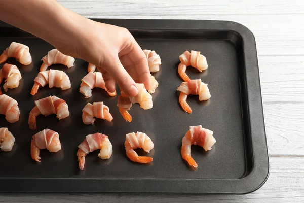 Woman putting bacon-wrapped shrimps — Stock Photo, Image