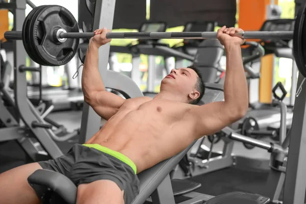 Musculoso hombre de entrenamiento con barra en el gimnasio —  Fotos de Stock