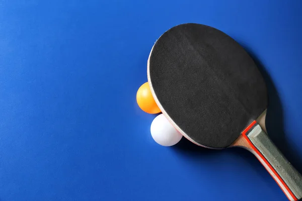 Ракетка для пинг-понга и мячи на синем фоне — стоковое фото