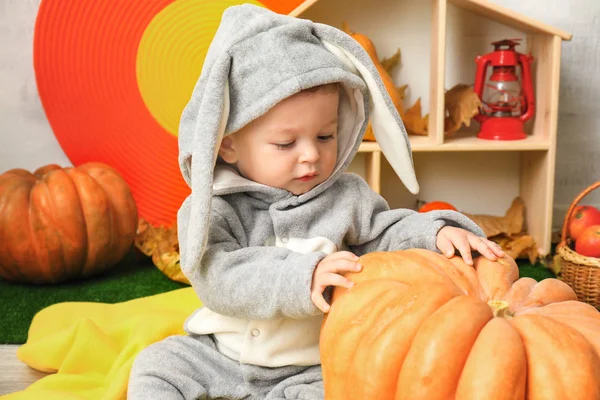 Entzückendes Baby im Hasenkostüm posiert mit Kürbis drinnen — Stockfoto