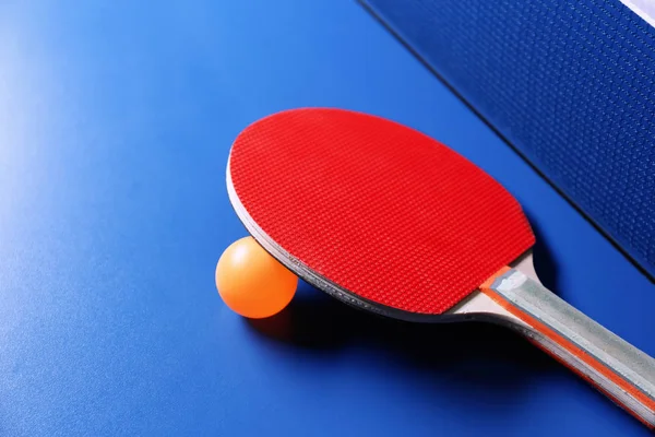 Raqueta de ping pong y pelota cerca de la red en la mesa —  Fotos de Stock