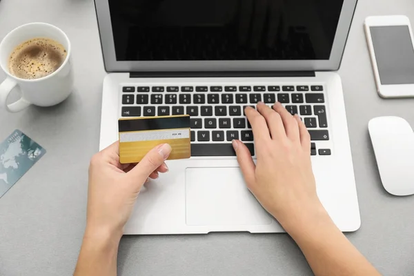 Женщина с кредитной картой и ноутбуком за столом — стоковое фото
