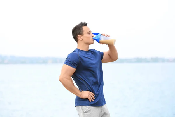 Joven guapo con batido de proteínas — Foto de Stock