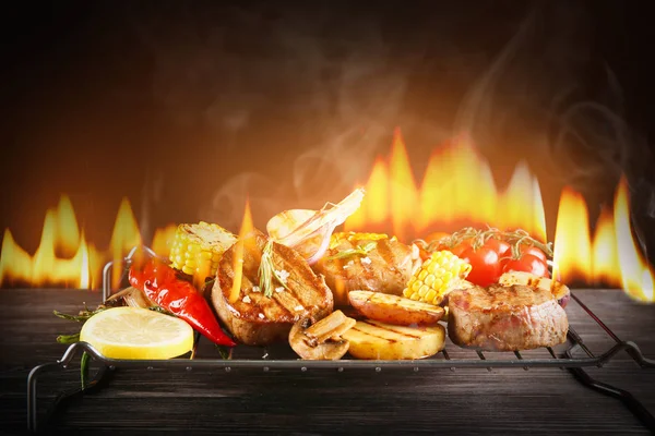 Tasty grilled steaks with vegetables and flame — Stock Photo, Image