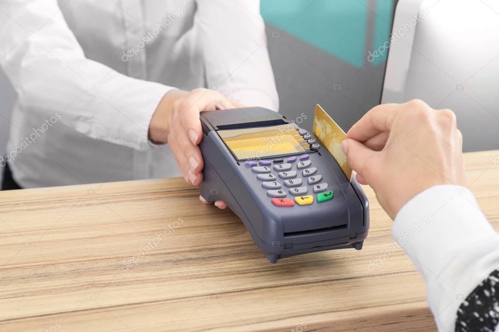 Woman using bank terminal for credit card payment indoors