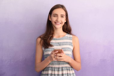Renk arka plan üzerinde cep telefonu ile çekici genç kız