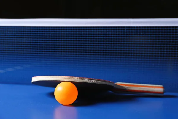 Ping pong racket and ball near net on table — Stock Photo, Image