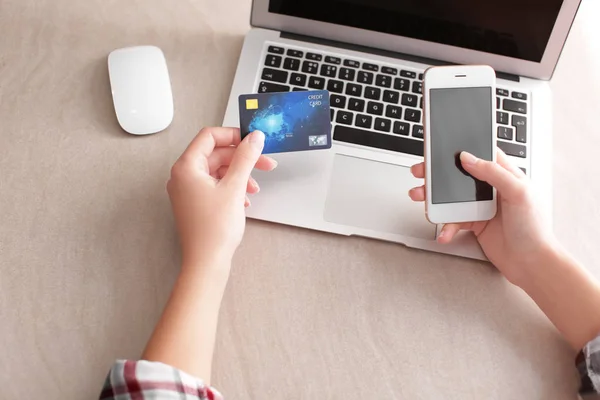 Vrouw met creditcard, laptop en mobiele telefoon aan tafel — Stockfoto