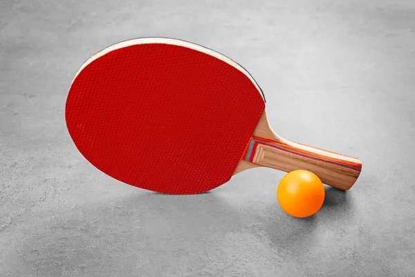 Tischtennisschläger und Ball auf grauem Hintergrund — Stockfoto