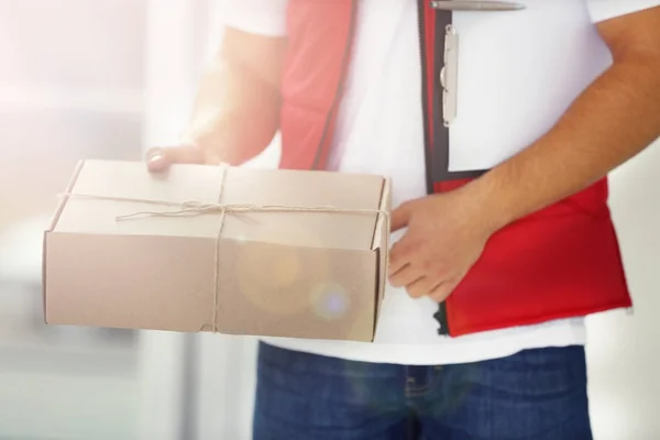 Entrega hombre en paquete de sujeción uniforme en el interior — Foto de Stock