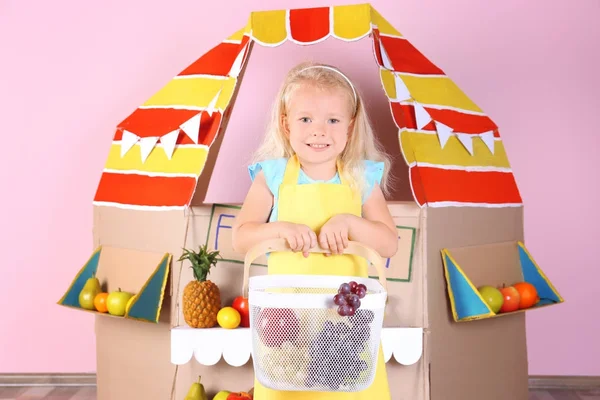 Meyve ve karton durak arka plan üzerinde küçük kızla — Stok fotoğraf