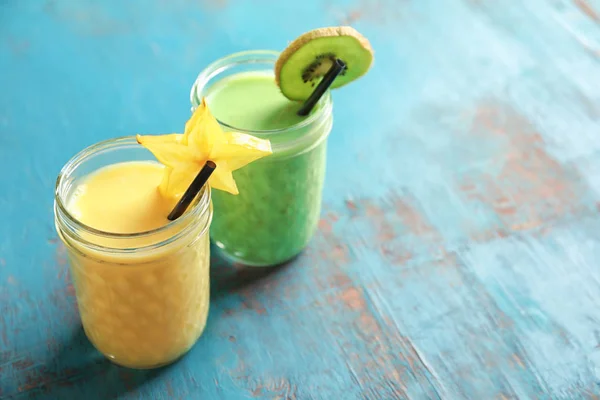 Bril met verschillende milkshakes op kleur achtergrond — Stockfoto