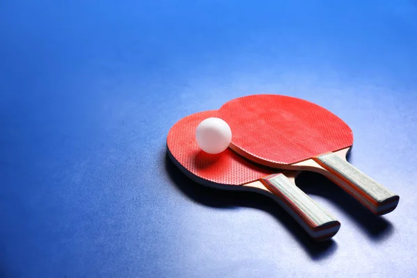 Duas raquetes de pingue-pongue e bola no fundo azul — Fotografia de Stock