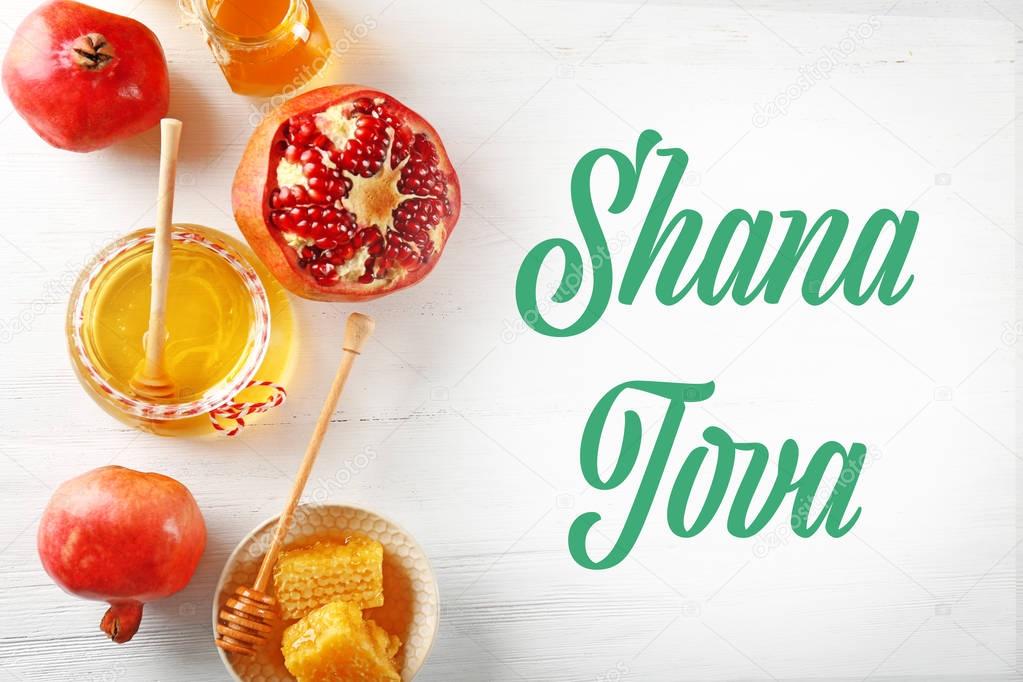 Text SHANA TOVA and traditional holiday food on wooden background