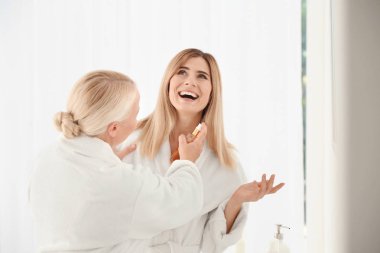 Kozmetik ürünleri kullanarak kızı ile olgun kadın