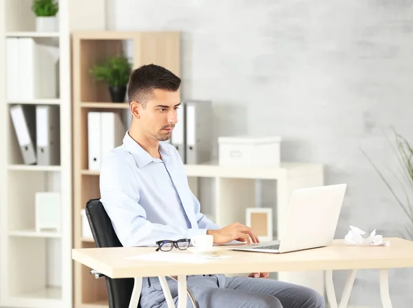 Homme attrayant avec ordinateur portable au bureau — Photo