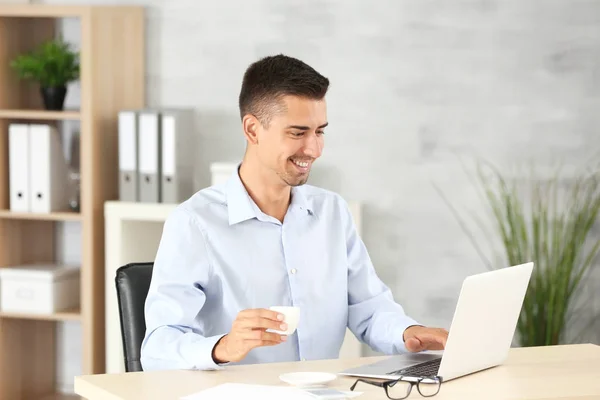 Homme attrayant avec ordinateur portable au bureau — Photo