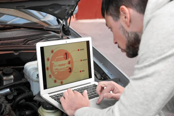 Mladý muž mechanik užívající počítač diagnostiky při opravě vozu — Stock fotografie