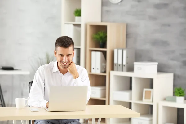 Homem atraente com laptop no escritório — Fotografia de Stock