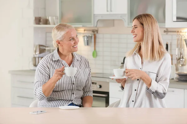 Молодая женщина пьет чай с пожилой матерью дома — стоковое фото