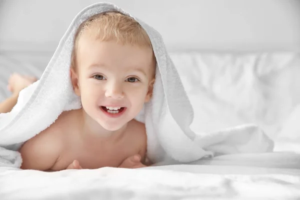 Netter kleiner Junge mit Handtuch auf dem Bett zu Hause — Stockfoto