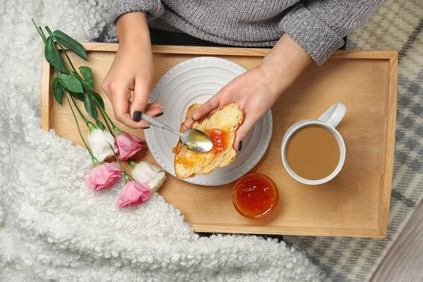 Woman spreading jam over croissant — Stock Photo, Image