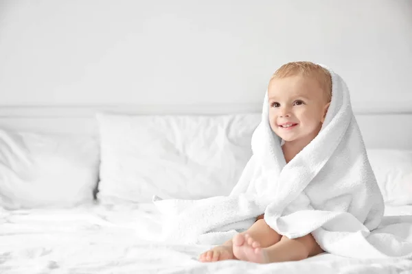 Menino bonito com toalha na cama em casa — Fotografia de Stock