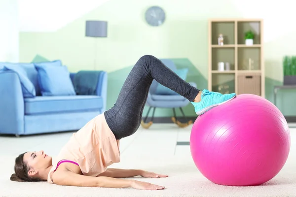 Hermosa joven haciendo ejercicios con pelota de fitness en casa —  Fotos de Stock