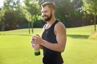 Protein shake açık havada ile sportif genç adam