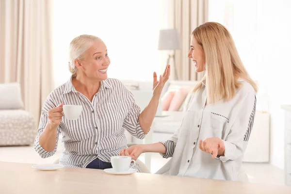 Jonge vrouw drinken van thee met bejaarde moeder thuis — Stockfoto