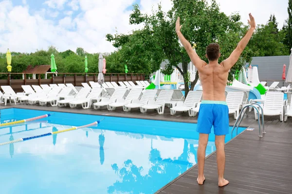 Handsome young man near blue swimming pool — Stock Photo, Image