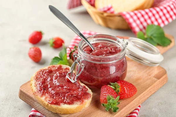 Jar and piece of bread with strawberry jam — Stock Photo, Image