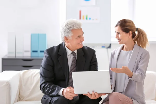 Uomo anziano e giovane donna seduti sul divano in ufficio — Foto Stock