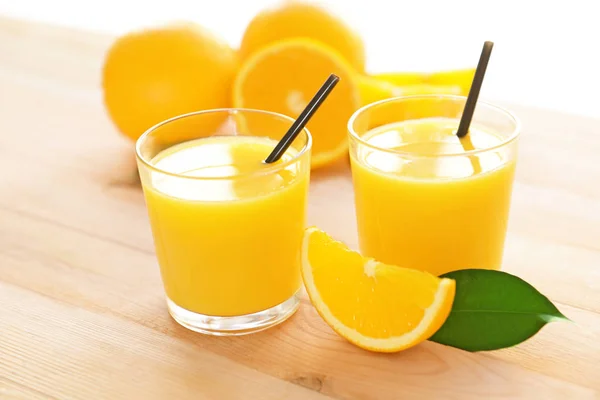 Óculos com delicioso suco de laranja fresco na mesa de madeira — Fotografia de Stock