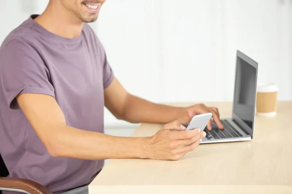 Человек со смартфоном и ноутбуком в офисе — стоковое фото