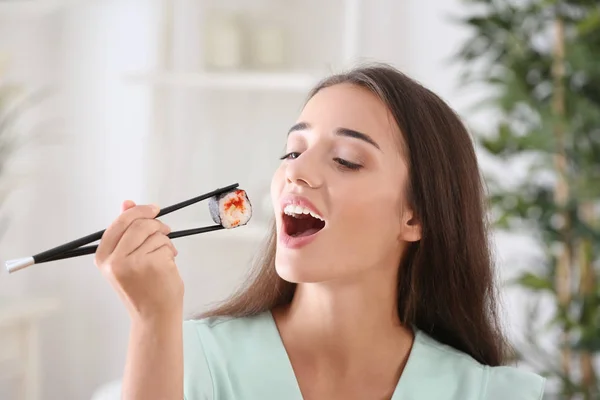 Mujer joven comiendo sushi roll —  Fotos de Stock