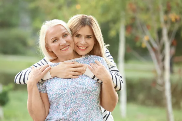 Mujer joven con madre anciana al aire libre — Foto de Stock