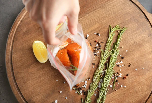 Женщина открывает пластиковый пакет с маринованными ломтиками лосося — стоковое фото