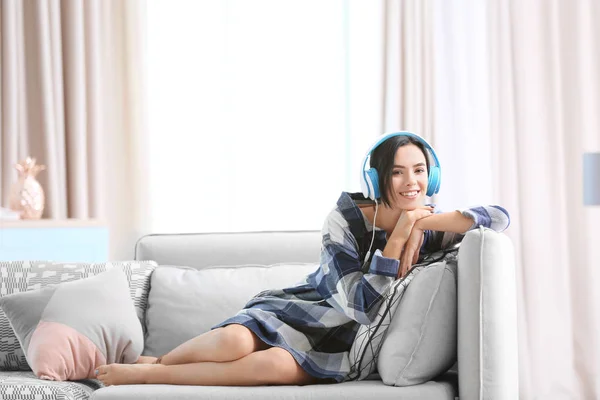 Mladá žena poslechu hudby přes sluchátka doma — Stock fotografie