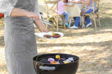Adam açık havada mangal üzerinde lezzetli biftek pişirme
