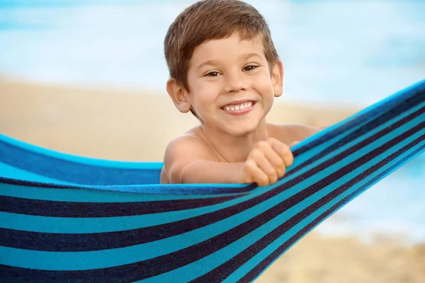Netter kleiner Junge liegt in der Hängematte am Strand des Resorts — Stockfoto