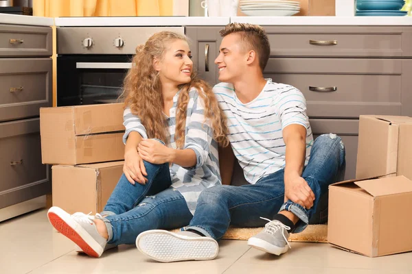 Pareja joven con cajas móviles en el suelo en la cocina —  Fotos de Stock