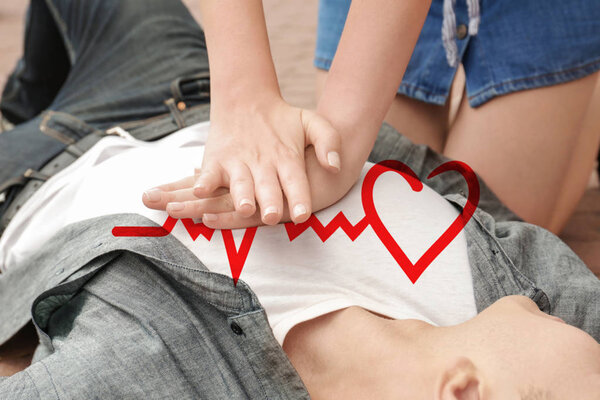 Woman giving first aid to man with heart attack outdoors