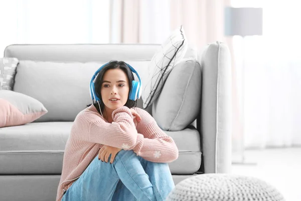 Молода жінка слухає музику через навушники вдома — стокове фото