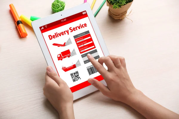Woman tracking parcel with help of tablet app at table
