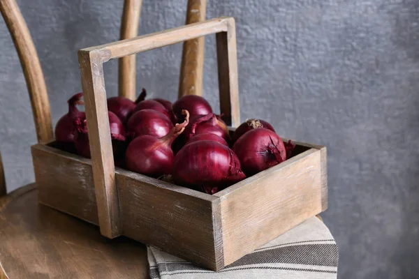 Caja de madera con cebollas rojas en silla —  Fotos de Stock